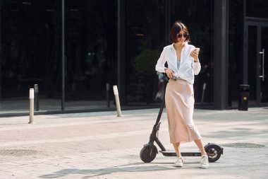 Modern binaya karşı. Güzel, genç bir bayan dışarıda motosikletiyle bekliyor..