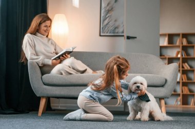 Anne ve kızı evde Malta köpeğiyle birlikte..