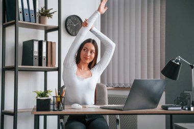 Egzersiz molası. Beyaz elbiseli genç ve güzel bayan ofiste..