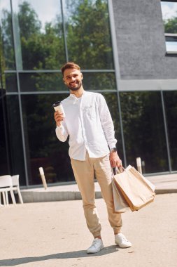 Neşeli bir ruh hali. Şık genç adamın alışveriş günü var. Çantalarla dışarıda..