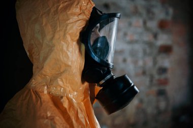 Yan görüş. Kıyamet sonrası binanın harabelerinde kimyasal koruma kıyafeti giymiş bir adam..