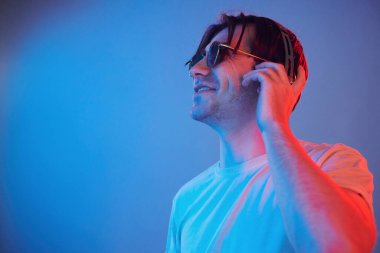 Side view. Man standing in the studio with neon light.