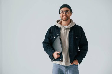 Şapka ve gözlüklerde bilgisayar uzmanıyım. Yakışıklı adam stüdyoda beyaz arka plana karşı..