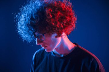 Aşağıya bakıyorum. Kıvırcık saçlı genç adam kapalı alanda neon ışıkla aydınlatılır..