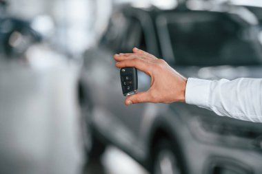 Anahtarların görüntüsünü kapat. Beyaz elbiseli genç adam araba galerisinde..