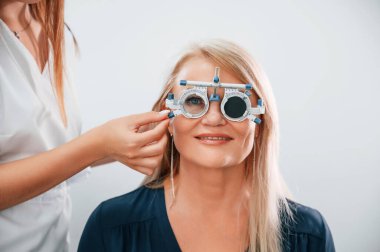 Gözlük takıyordu. Kadının görüşü özel bir cihaz kullanan klinik çalışanı tarafından test ediliyor..