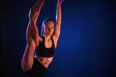 Bacağını kaldır, egzersiz yap. Güzel kaslı kadın stüdyoda neon ışıklı..