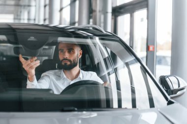 Beyaz elbiseli genç adam araba galerisinde..