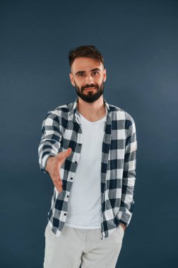 Alkışlar, selamlar. Yakışıklı adam stüdyoda mavi arka planda..