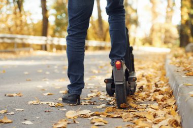 Yolda bir adamın sürdüğü eletric scooter 'ın yakın görüntüsü.