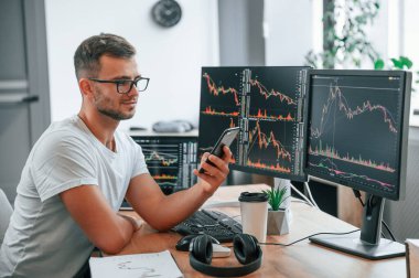 Genç borsacı ofiste bilgisayar kullanarak çalışıyor..