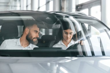 Otomobilde oturan kadın. Beyaz elbiseli adam araba galerisinde..