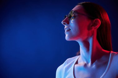 Durup poz vermek. İçerideki neon ışıkta duran genç bir kadının portresi..