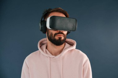 VR gözlüklü. Yakışıklı adam stüdyoda mavi arka planda..