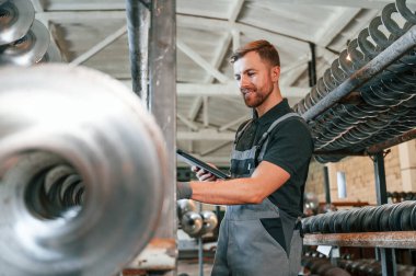 Tableti tutuyorum. Üniformalı adam iş yerinde tarım tekniğinin detaylarını geliştiriyor..