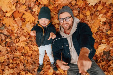 Düşen yapraklarla kaplı yerde yatıyordu. Baba ve küçük oğlu gündüz vakti dışarıda beraberler..