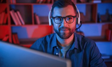 Okuma ve mavi neon ışıkları. Adam evde bilgisayarın başında oturuyor..