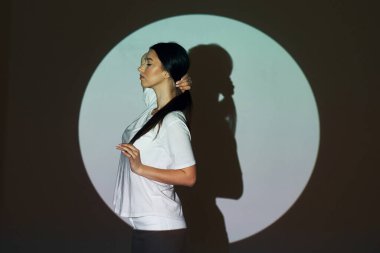 Çember ve gölge. Stüdyoda projektör neon ışıkları altında güzel genç bir kadın var..