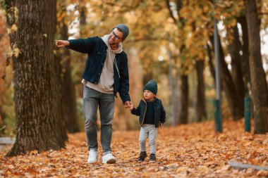 Babamın elinde bir şey var. Baba ve küçük oğlu gündüz vakti dışarıda beraberler..
