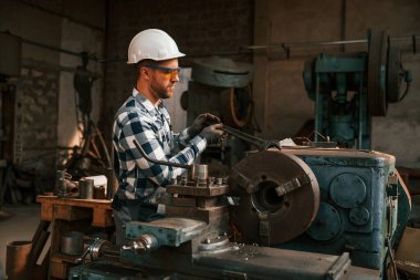 Koruyucu gözlüklü ve kasklı. Üniformalı fabrika çalışanı içeride..