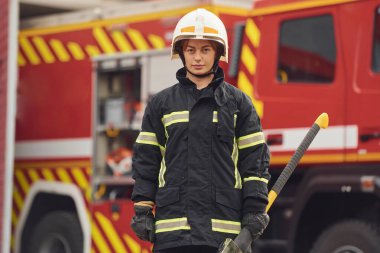 Elinde baltayla kamyona karşı duruyorsun. Üniformalı kadın itfaiyeci departmanda çalışıyor..