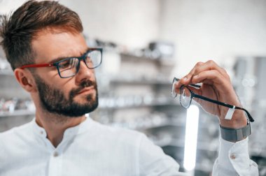 Modern görünüş. Optik mağazasından gözlük seçen sakallı şık bir adam..