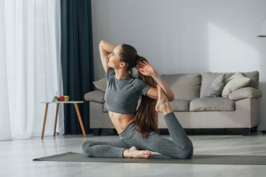 Eller uzanıyor. İnce vücutlu ve yoga elbiseli genç bir kadın evde..