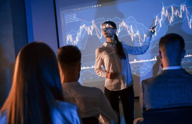 Projektördeki grafikler. Kadın lider borsa şirketinde çalışanlarla konuşuyor..