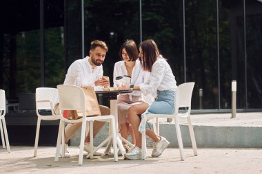 Sandalyelerde otururken. Üç arkadaş dışarıda harika bir hafta sonu geçiriyorlar..