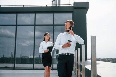 İçki ve not defteri tutuyor. Kadın ve erkek dışarıda inşaat projesinde birlikte çalışıyorlar..