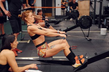 Yan görüş. Spor salonunda kürek çeken sporcu bir kadın..