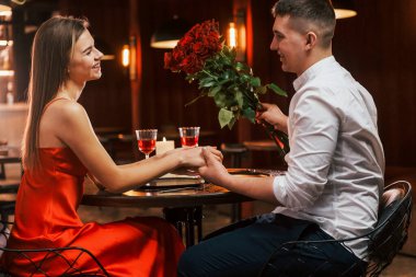 Adam güzel çiçekler veriyor. Romantik çift restoranda yemek yiyor..