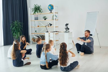 Adam jest dili öğretiyor. Okulda öğretmenle birlikte bir grup çocuk öğrenci..