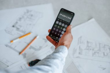 Akıllı telefon kullanarak numaralar hesaplanıyor. Plan zeminde. Adam dairede tamirat yapıyor..