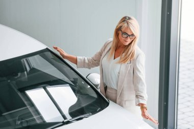 Beyaz elbiseli kadın araba galerisinde..