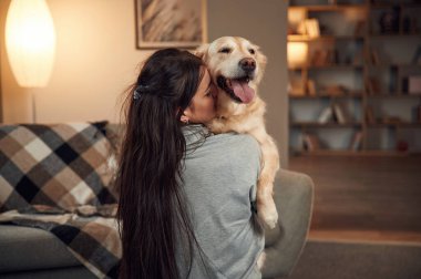 Köpeği elinde tutuyor. Kadın Golden Retriever 'la evde..