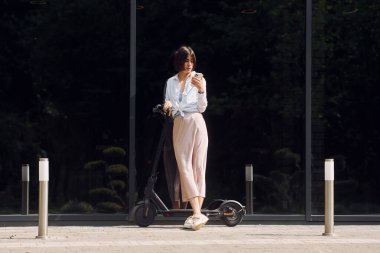 Telefonla. Güzel, genç bir bayan dışarıda motosikletiyle bekliyor..