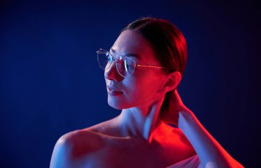 Göz giysisiyle. İçerideki neon ışıkta duran genç bir kadının portresi..