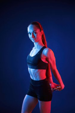 Stüdyoda, kırmızı ve mavi ışıklı. Güzel kaslı kadın içeride..