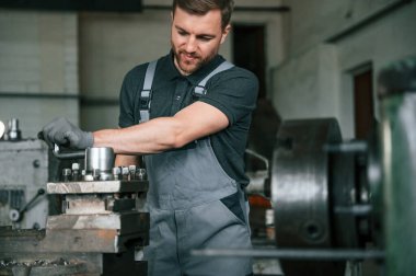 Metalle çalışmak. Üniformalı adam içeride tarım tekniğinin detaylarını geliştiriyor..