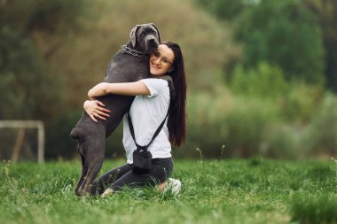 Evcil hayvanı kucaklamak. Genç esmer kız köpeğiyle dışarıda yürüyüş yapıyor..
