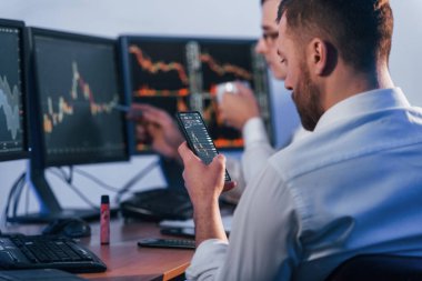 Yoğun bir gün. Ofiste değişim teknolojisiyle çalışan iki borsacı..