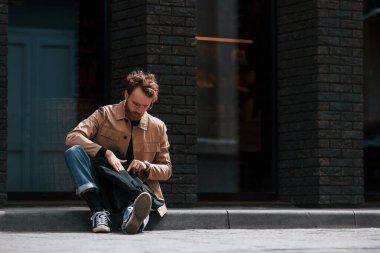 Kaldırımda oturuyordum. Sakallı, haki renkli ceketli ve kot pantolonlu şık bir adam binanın yanında..