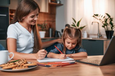 Çizim yapmayı öğreniyorum. Genç anne kızıyla birlikte dairede..