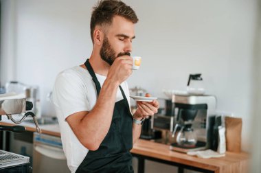 Lezzetli kahve tadı. Beyaz gömlekli ve siyah önlüklü kafe çalışanı içeride..