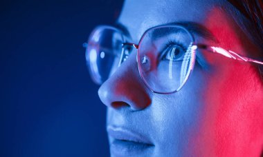 Gözlüklü. Manzarayı kapat. Stüdyoda neon ışıkla aydınlatılmış genç ve güzel bir kadın var..