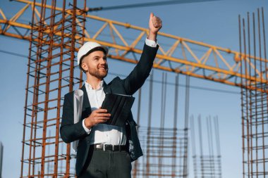 El hareketleriyle emirler veriyor. Resmi kıyafetli bir işadamı gün içinde şantiyede olacak..