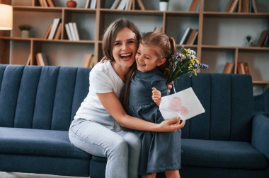 Birbirinize sarılın. Hediyeyi veriyorum. Genç anne kızıyla birlikte dairede..