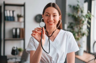 Elinde steteskopla. Beyaz önlüklü güzel bayan doktor ofiste..