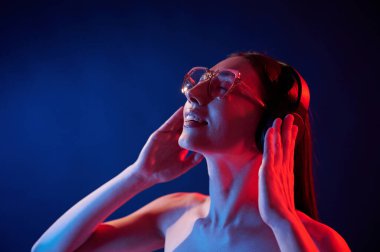 Kulaklıkla. İçerideki neon ışıkta duran genç bir kadının portresi..